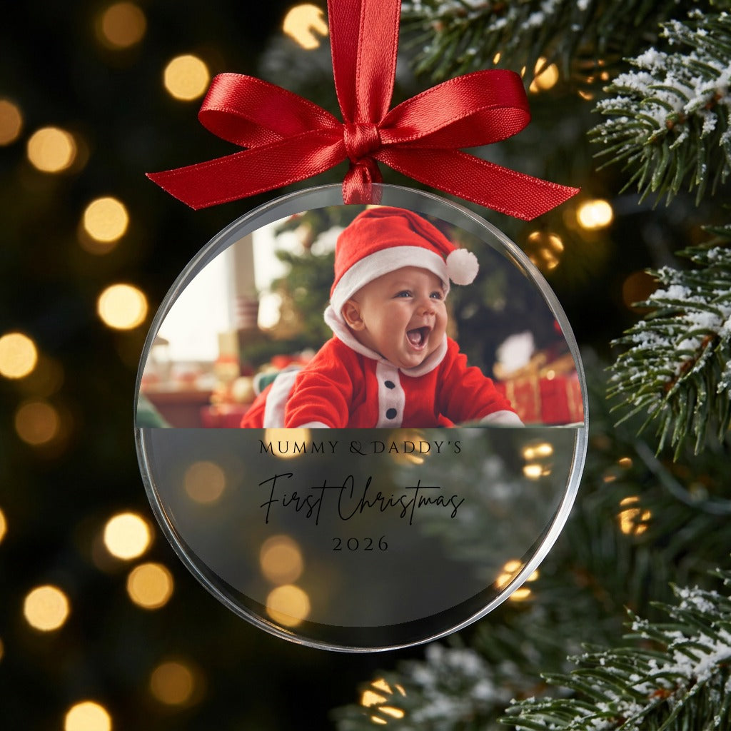 Mummy and Daddy first Christmas photo bauble with red ribbon on a Christmas tree with warm lights