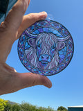 Highland Cow stained glass effect acrylic suncatcher held up to the sky