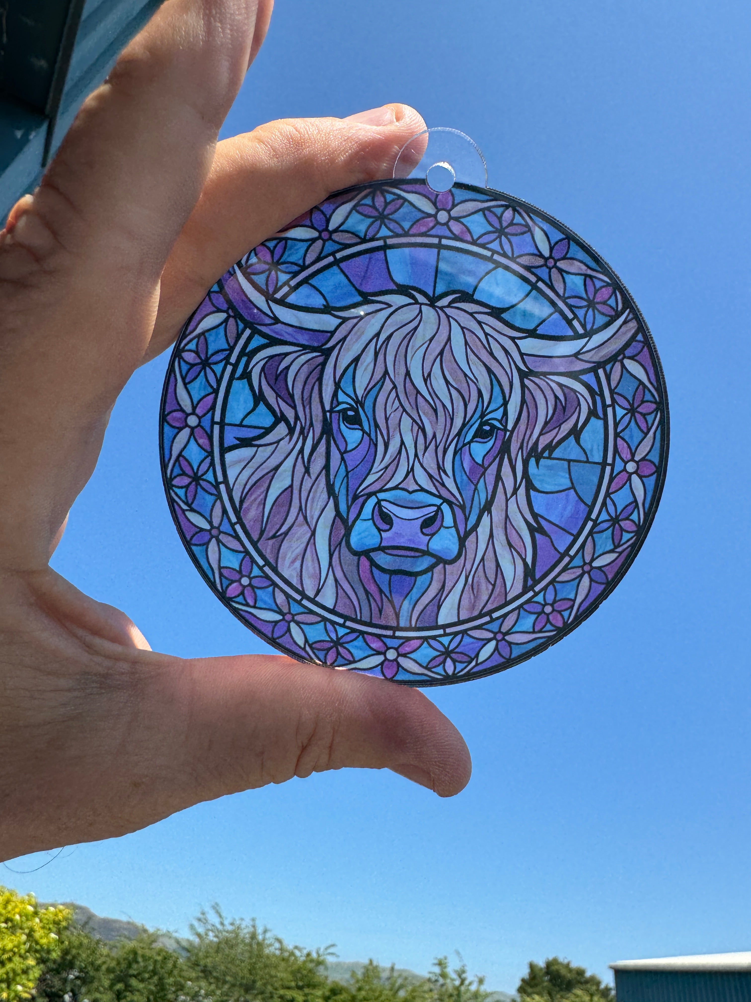 Highland Cow stained glass effect acrylic suncatcher held up to the sky