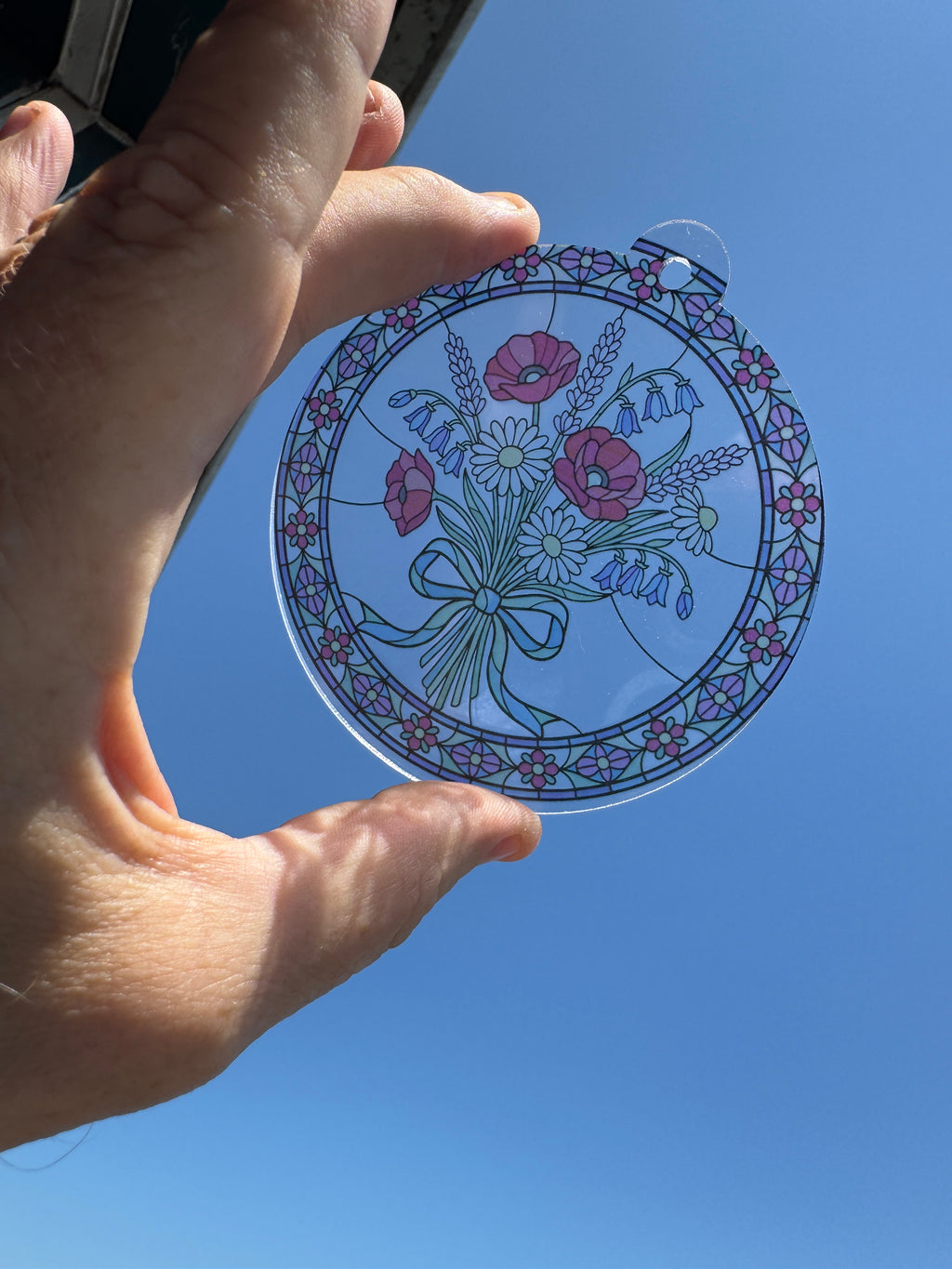 Wildflower bouquet stained glass effect acrylic suncatcher held up to the sky
